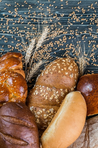 Surtido de panes y espigas sobre tabla de madera vieja, fondo de alimentos