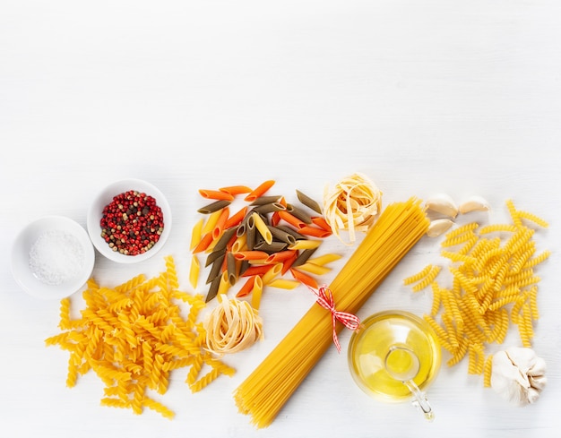 Surtido de pasta cruda plana yacía en blanco. espaguetis fusilli penne tagliatelle girandole