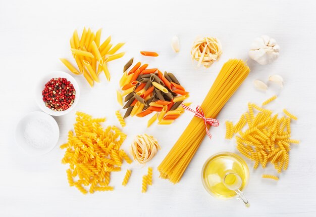 Surtido de pasta cruda plana yacía en blanco. espaguetis fusilli penne tagliatelle girandole