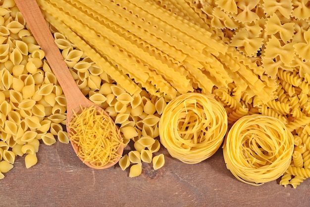 Foto surtido de pasta italiana cruda sobre un fondo de madera cerrar