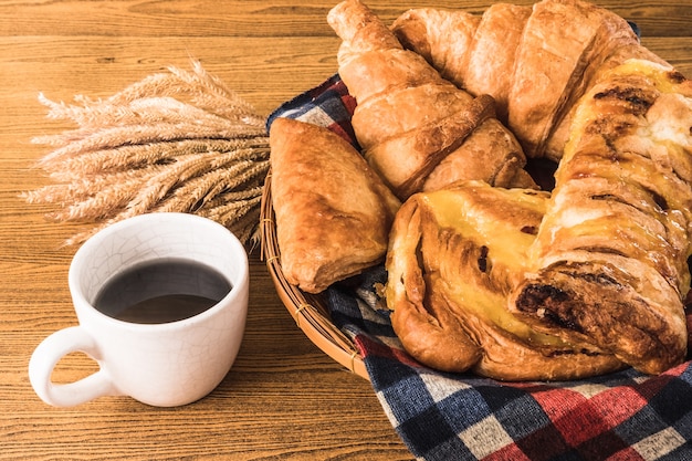 Surtido de pasteles con la taza de café en el fondo de la tabla de madera.