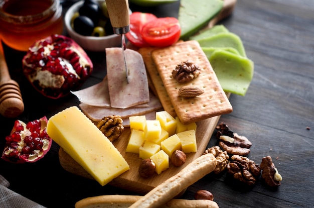 Surtido de piezas caseras de queso con miel, frutas, galletas y nueces en la mesa. Productos lácteos frescos, alimentos orgánicos saludables. Delicioso aperitivo.