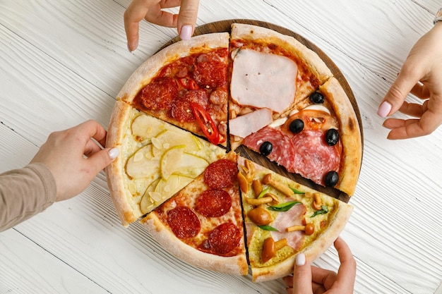 Surtido de pizza italiana en una mesa de madera blanca Diferentes piezas en una sola porción