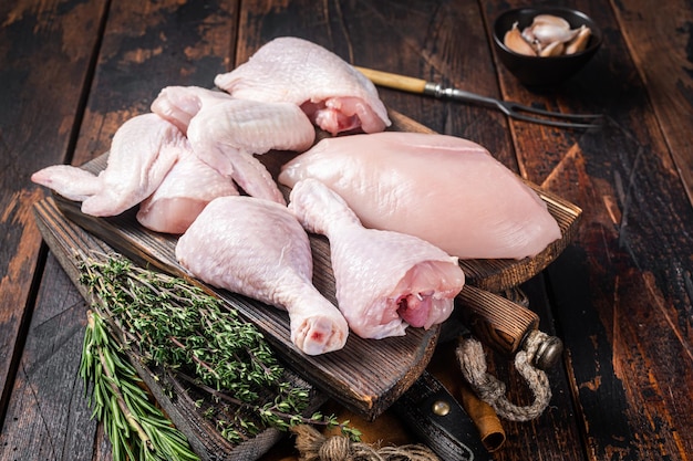 Surtido de porciones de pollo para asar a la parrilla Partes crudas Muslo Pechuga Filete Alas Muslo Fondo de madera Vista superior