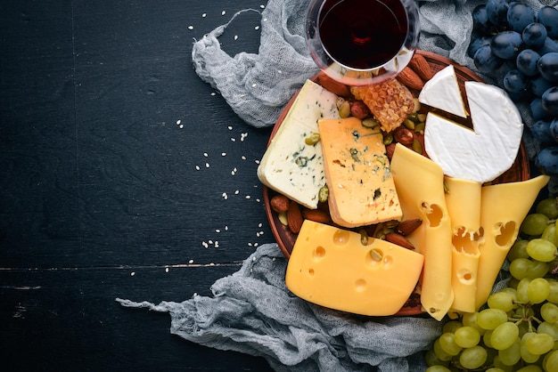 Surtido de quesos una botella de vino miel nueces y especias en una mesa de madera Vista superior Espacio libre para texto