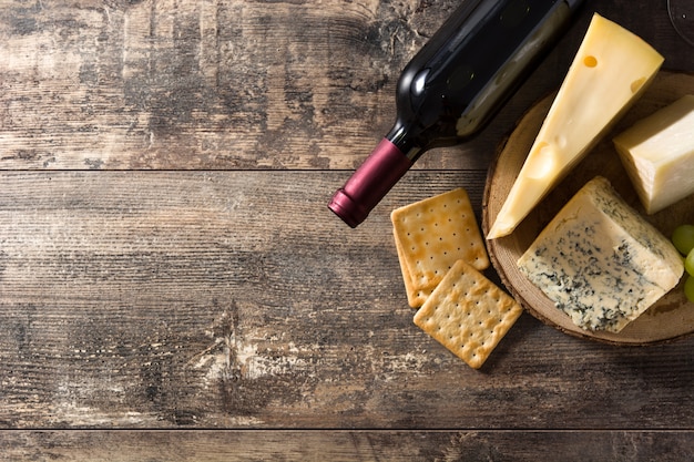 Foto surtido de quesos y vinos en mesa de madera. vista superior