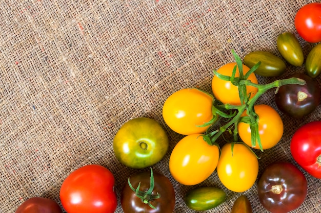 Surtido de tomates frescos coloridos en tela de saco