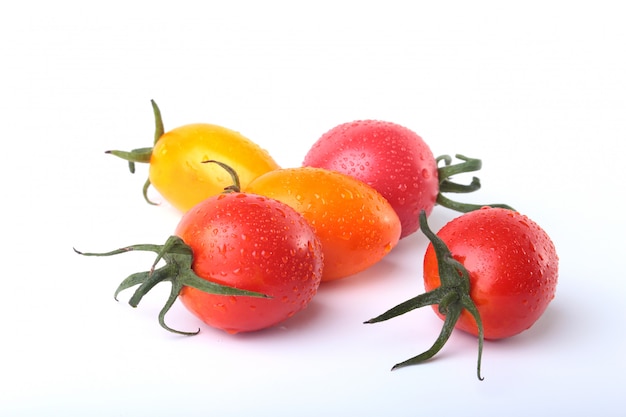 Surtido de tomates frescos con hojas verdes aisladas sobre fondo blanco.