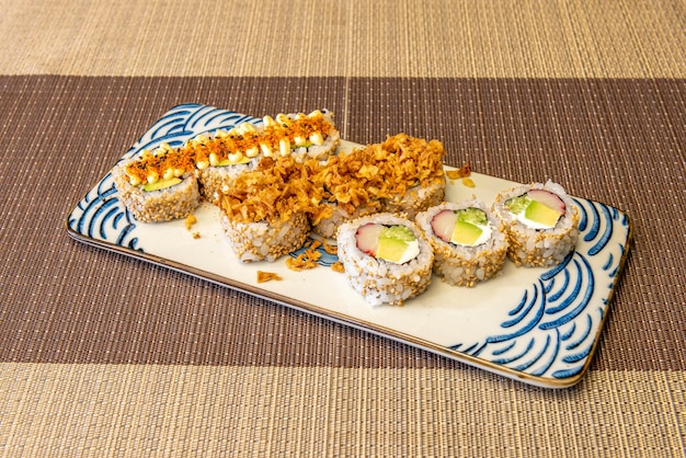 Surtido de uramaki con semillas de sésamo y relleno de queso Filadelfia con surimi, huevas de aguacate y cebolla crujiente