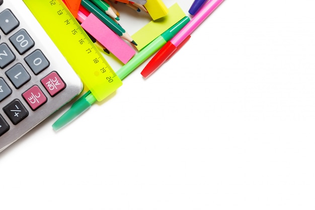 Surtido de útiles escolares, incluidos bolígrafos, lápices, tijeras, pegamento y una regla, sobre un fondo blanco.
