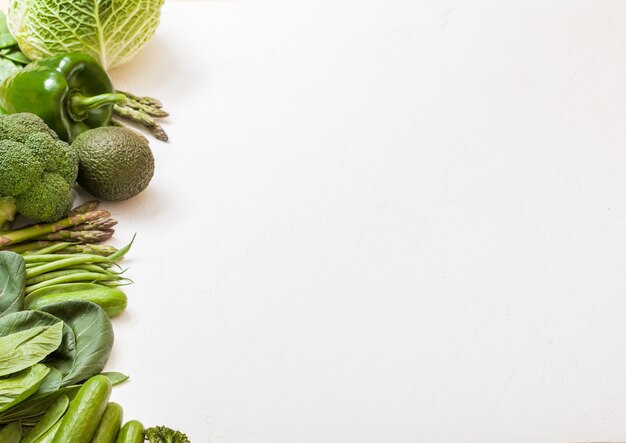 Foto surtido verde tonificado vegetales orgánicos crudos en mesa blanca.