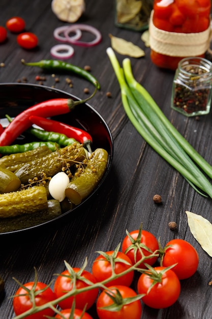 Surtido de verduras en escabeche en un plato negro sobre un fondo oscuro