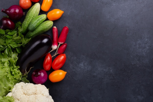 Surtido de verduras orgánicas crudas sobre fondo de piedra oscura