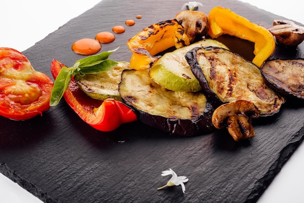 Surtido de verduras a la parrilla en tablero de madera oscura.