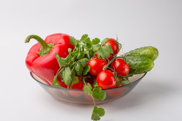 Surtido de verduras: tomates, pimientos rojos, pepinos en un plato sobre un blanco