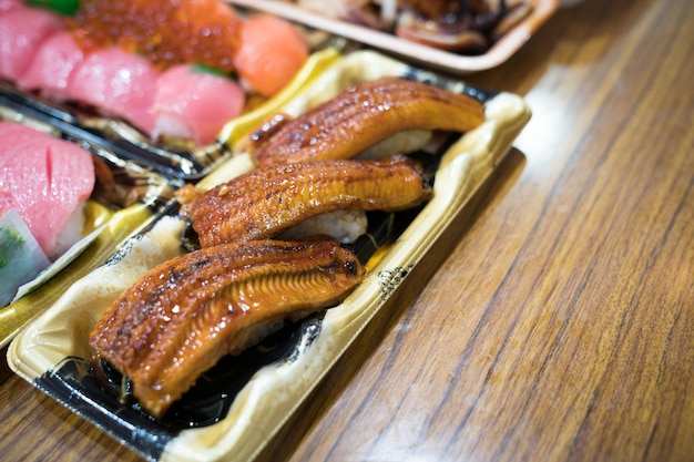 Sushi de anguila y otros sushi; salmón, otoro, cutre, camarones a la plancha, cangrejo se disponen sobre la mesa listos para comer.