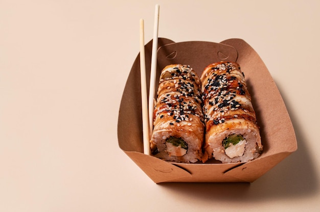 Sushi asiático Sushi con salsa de anguila y sésamo en un recipiente de papel sobre un fondo claro