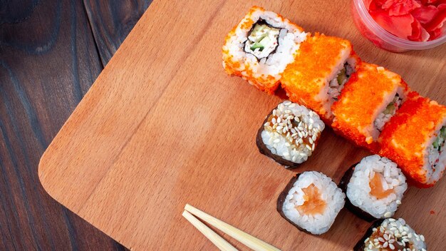 Sushi auf einem Holzbrett mit Stäbchen