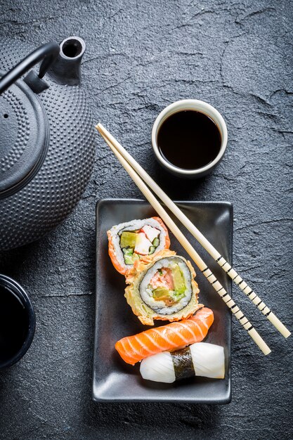 Foto sushi auf einem schwarzen teller mit stäbchen