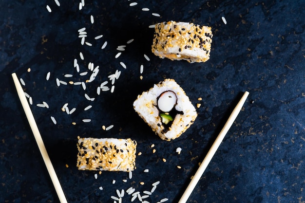 Sushi auf einer schwarzen Tischplatte mit Essstäbchen aus Holz Essen japanisches Essen im Restaurant