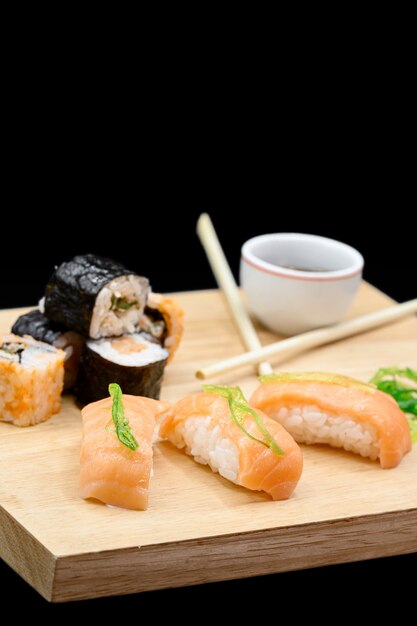 Sushi auf Holztisch auf schwarzem isoliertem Hintergrund.