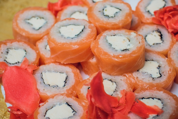 Sushi bellamente decorado en un plato y palillos cerca. El sushi es la comida tradicional asiática y japonesa. Rollo de sushi elaborado a base de pescado crudo y un arroz especial. Dieta de alimentos saludables.