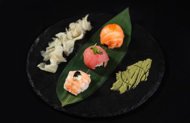 Sushi y camarones fritos con ajo en un plato de piedra con fondo negro