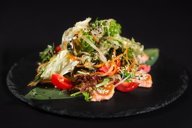 Sushi y camarones fritos con ajo en un plato de piedra con fondo negro