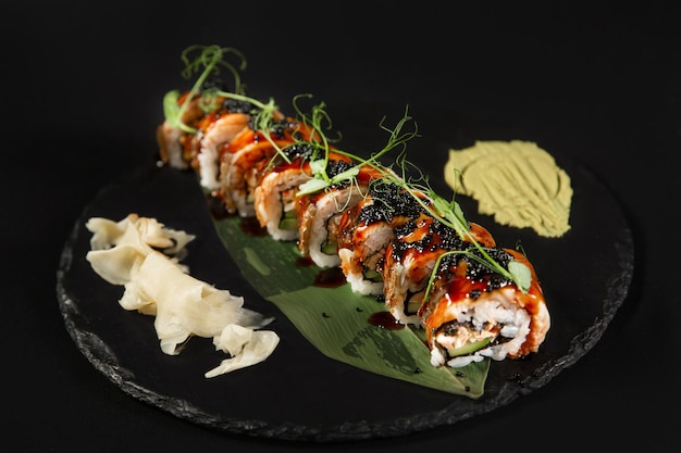 Sushi y camarones fritos con ajo en un plato de piedra con fondo negro