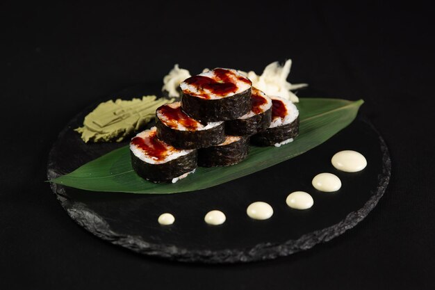 Sushi y camarones fritos con ajo en un plato de piedra con fondo negro