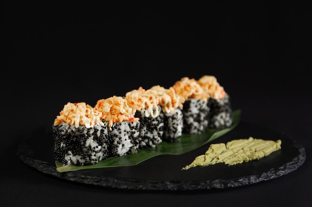 Sushi y camarones fritos con ajo en un plato de piedra con fondo negro