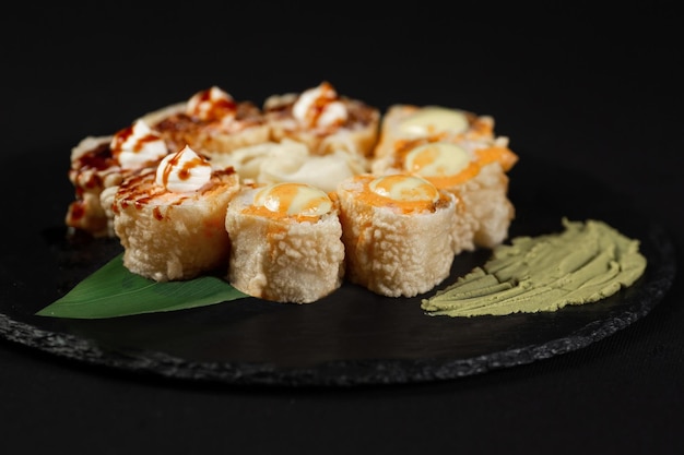 Sushi y camarones fritos con ajo en un plato de piedra con fondo negro