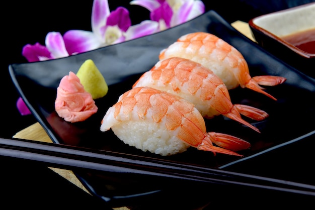 Sushi de camarones o sushi ebi japonés en placa negra con wasabi en iluminación flash.