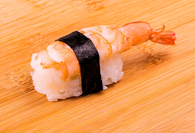 Sushi con camarones en un soporte de madera.