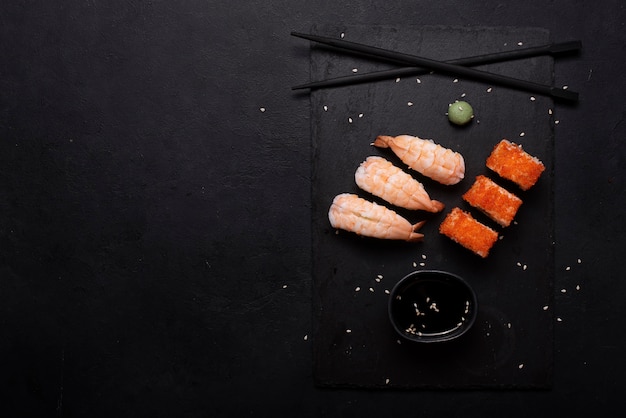 Sushi com camarão e rolinhos no quadro negro