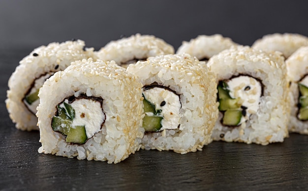 Sushi com salmão em um prato branco com hashis de soja gengibre wasabi em um fundo preto