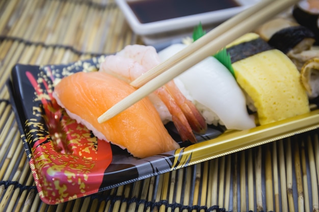 Sushi conjunto sashimi e rolos servidos no prato tradicional e esteira