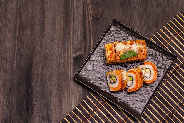 Sushi de camarão tigre grelhado. Rolo japonês ou coreano com diferentes ingredientes frescos. Fundo preto na moda