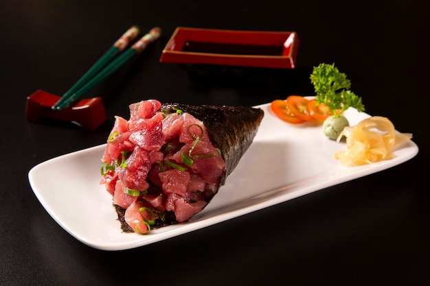 Sushi de temaki de atum em um prato branco em fundo preto