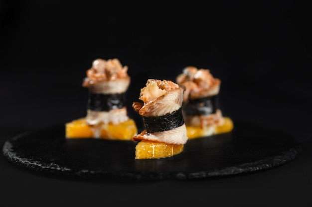 Sushi e camarão de alho frito em uma placa de pedra com fundo preto