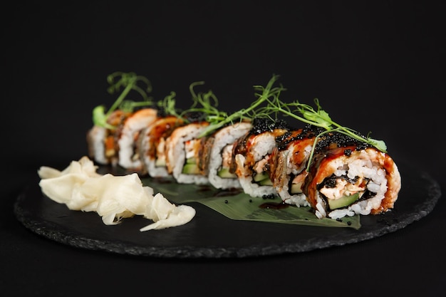 Sushi e camarão de alho frito em uma placa de pedra com fundo preto