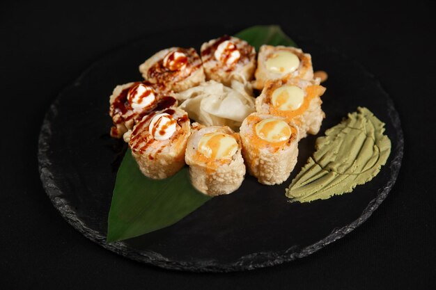 Sushi e camarão de alho frito em uma placa de pedra com fundo preto