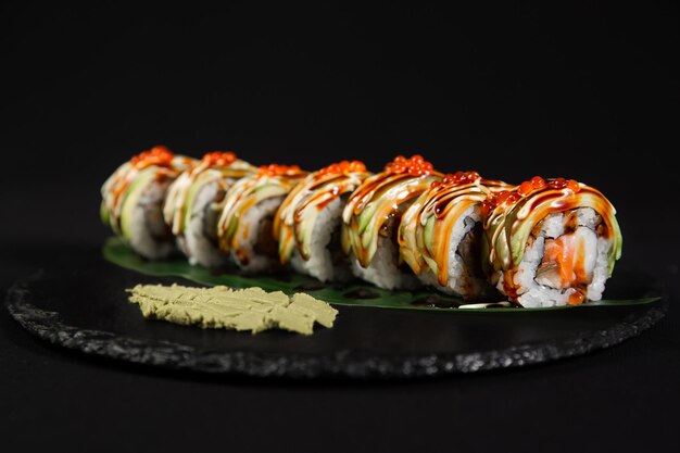 Sushi e camarão de alho frito em uma placa de pedra com fundo preto