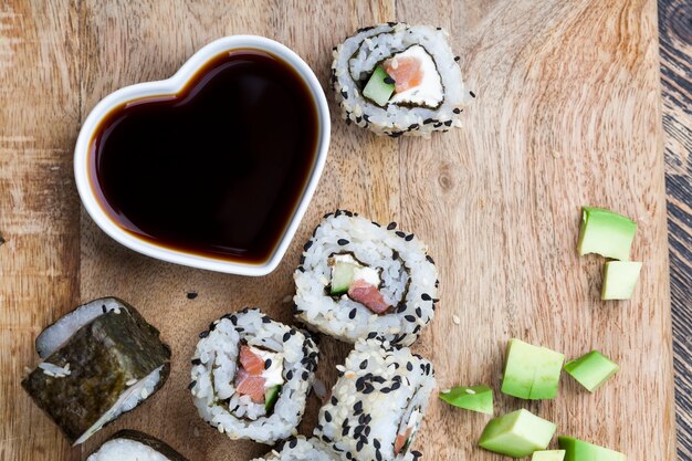 Sushi elaborado con arroz blanco, trucha y aguacate, productos vegetales listos para consumir y pescado rojo salmón