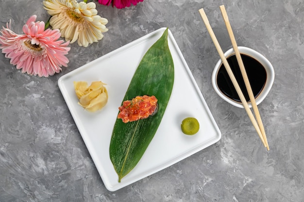 Sushi em folha de bananeira com molho em prato branco