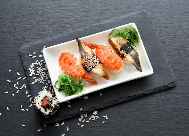 Foto sushi con ensalada en plato sobre una mesa de pizarra negra