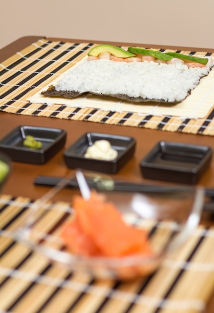 Foto sushi japonês com arroz pronto para rolar na mesa