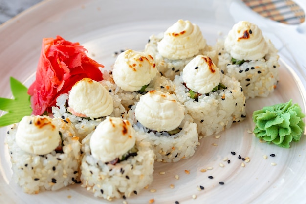 Sushi japonês com sementes de gergelim e cobertura de creme sobre fundo cinza