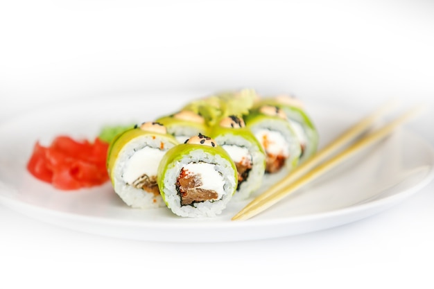 Sushi japonês de frutos do mar, roll e pauzinho em um prato branco com gengibre e wasabi