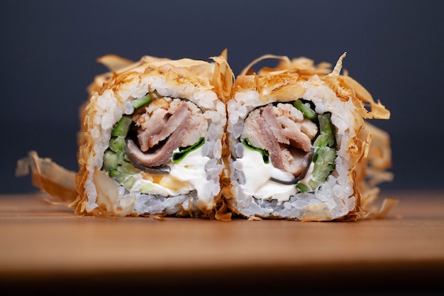 Sushi japonés roll con salmón y pepino en la oscuridad